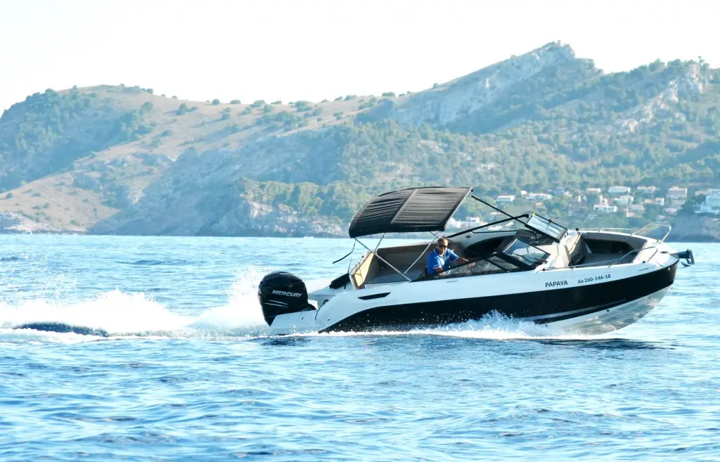 Motorboat with a sun canopy off the rocky coast