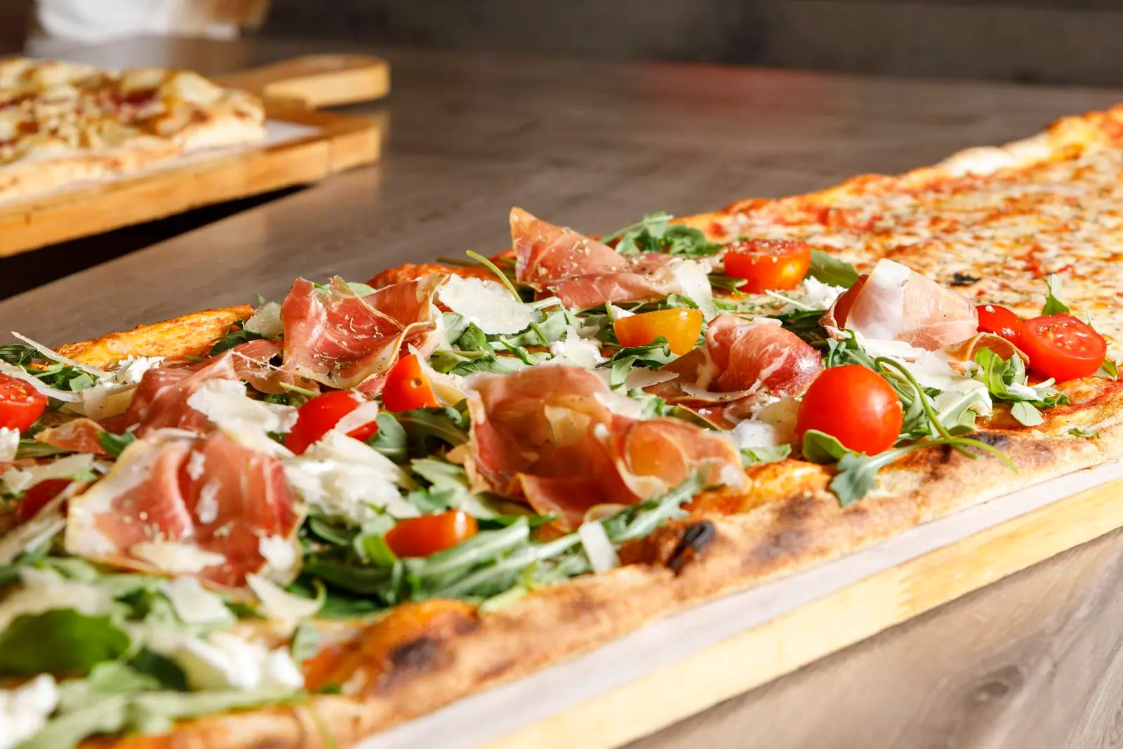 Long pizza with ham, tomatoes and greens at ENCANTO