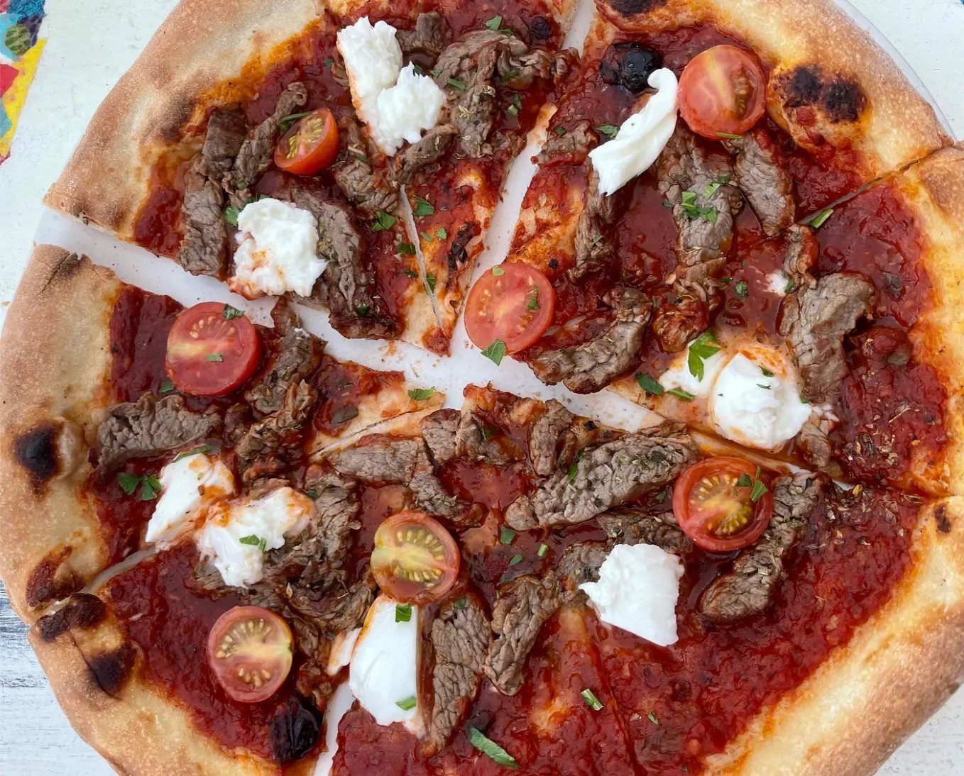 Pizza topped with tomatoes and white cheese